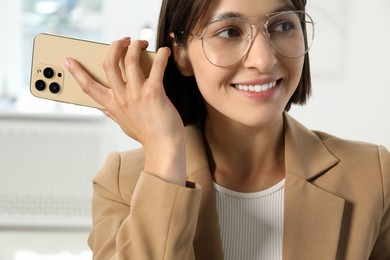 Beautiful woman with smartphone listening to voice message in office