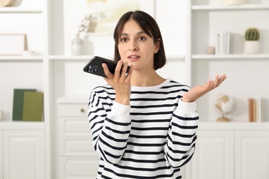 Photo of Beautiful woman recording voice message via smartphone at home