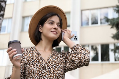 Photo of Beautiful woman with smartphone listening to voice message outdoors, low angle view