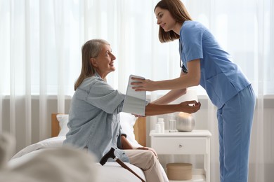 Photo of Smiling healthcare worker measuring patient's blood pressure indoors