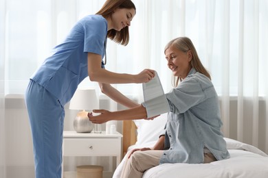 Photo of Smiling healthcare worker measuring patient's blood pressure indoors