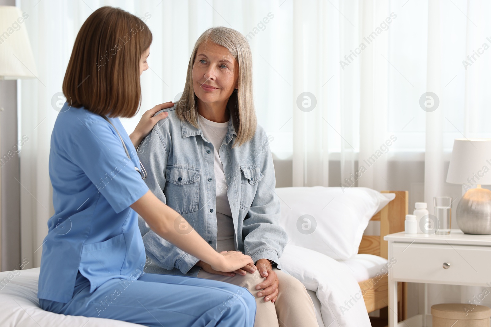 Photo of Healthcare worker supporting senior patient indoors. Space for text