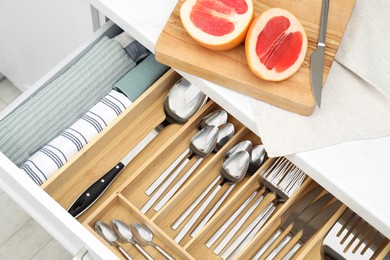 Photo of Box with cutlery in drawer, above view. Kitchen utensils storage