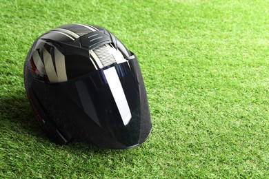 Modern motorcycle helmet with visor on green grass outdoors, space for text