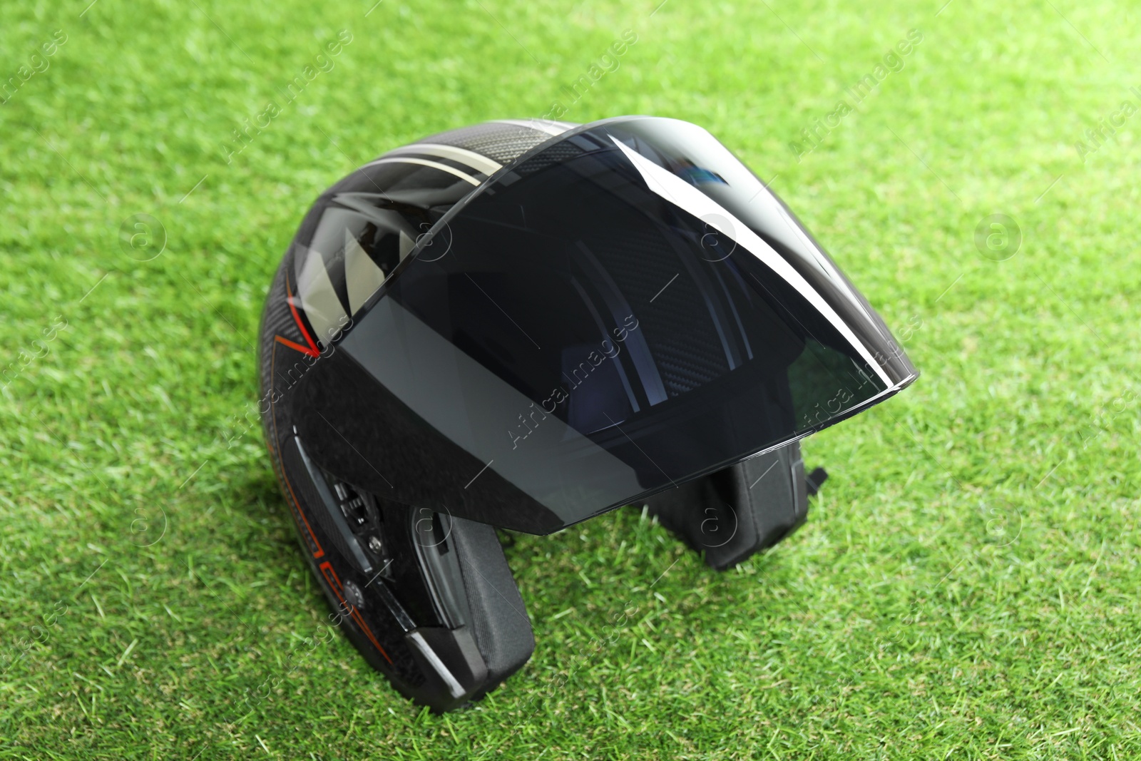 Photo of Modern motorcycle helmet with visor on green grass outdoors