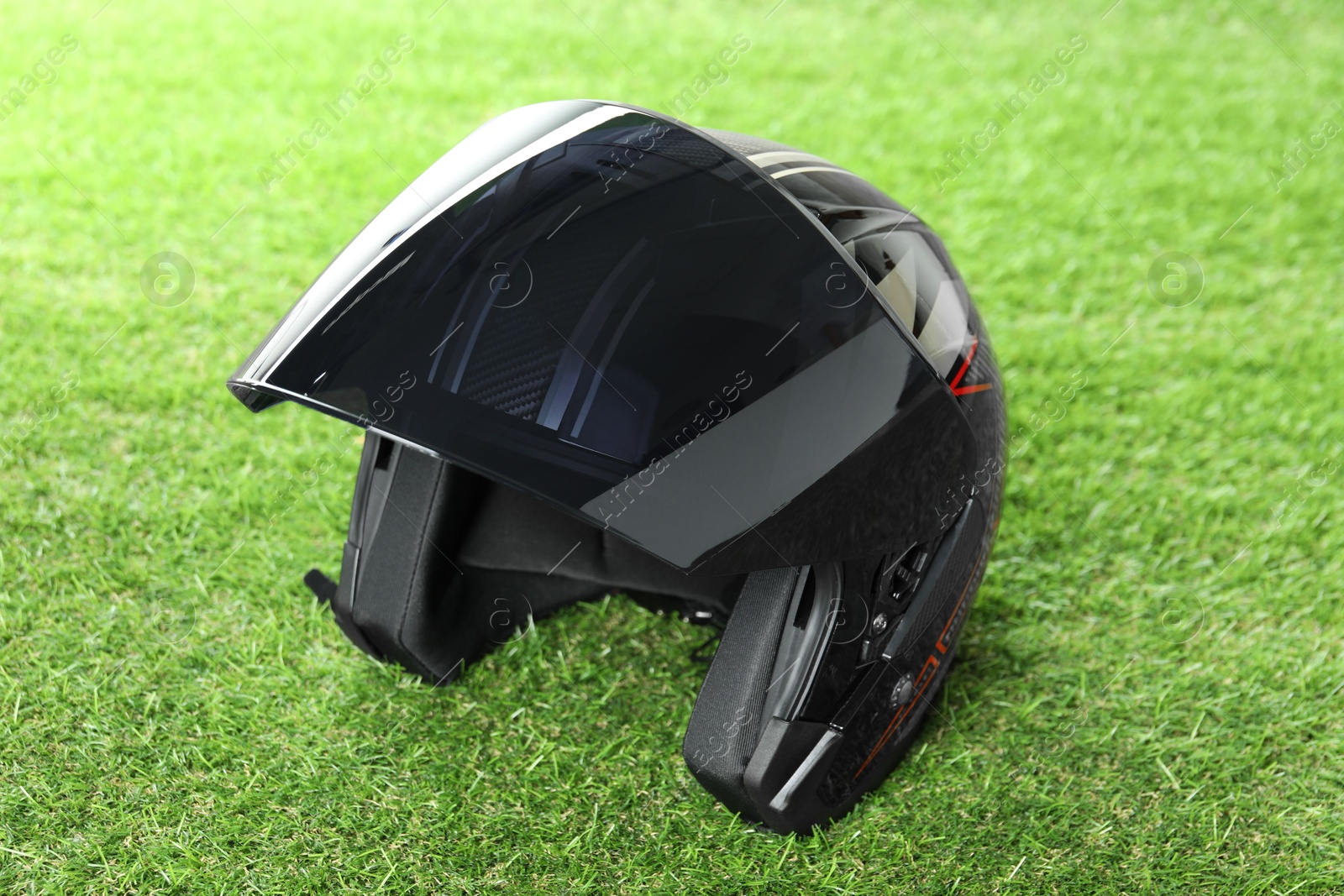 Photo of Modern motorcycle helmet with visor on green grass outdoors