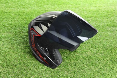 Modern motorcycle helmet with visor on green grass outdoors