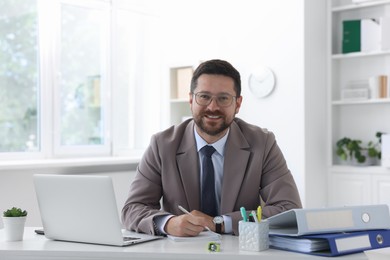 Photo of Portrait of smiling businessman at table in office