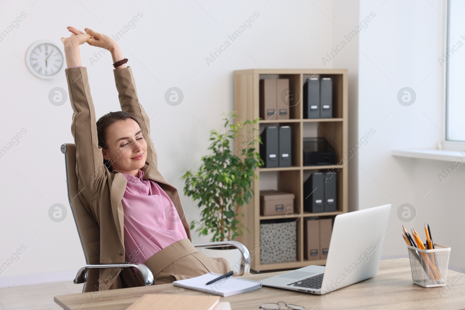 Photo of Businesswoman stretching at table in office. Break time