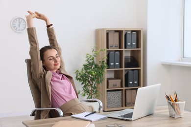 Photo of Businesswoman stretching at table in office. Break time