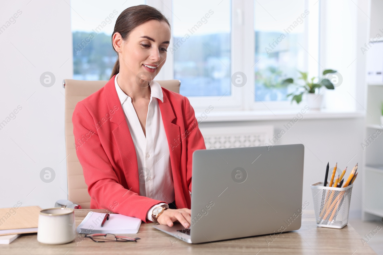 Photo of Smiling businesswoman working at table in office