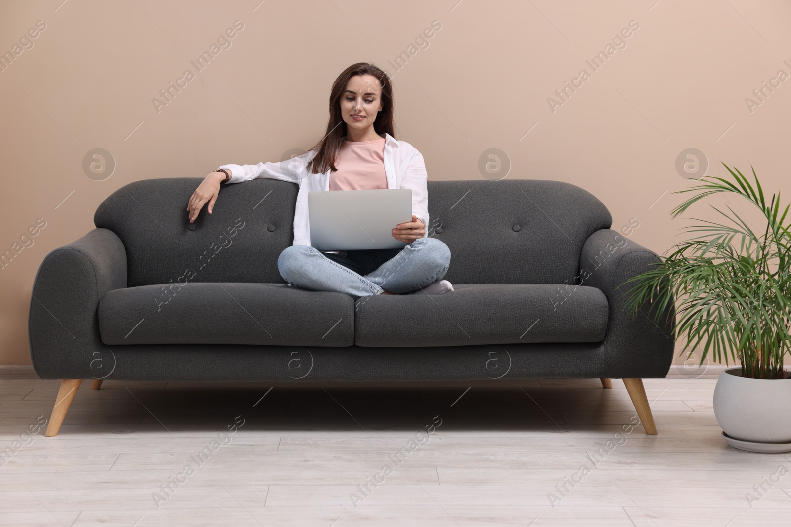 Photo of Smiling woman with laptop on sofa at home