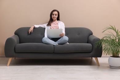 Smiling woman with laptop on sofa at home