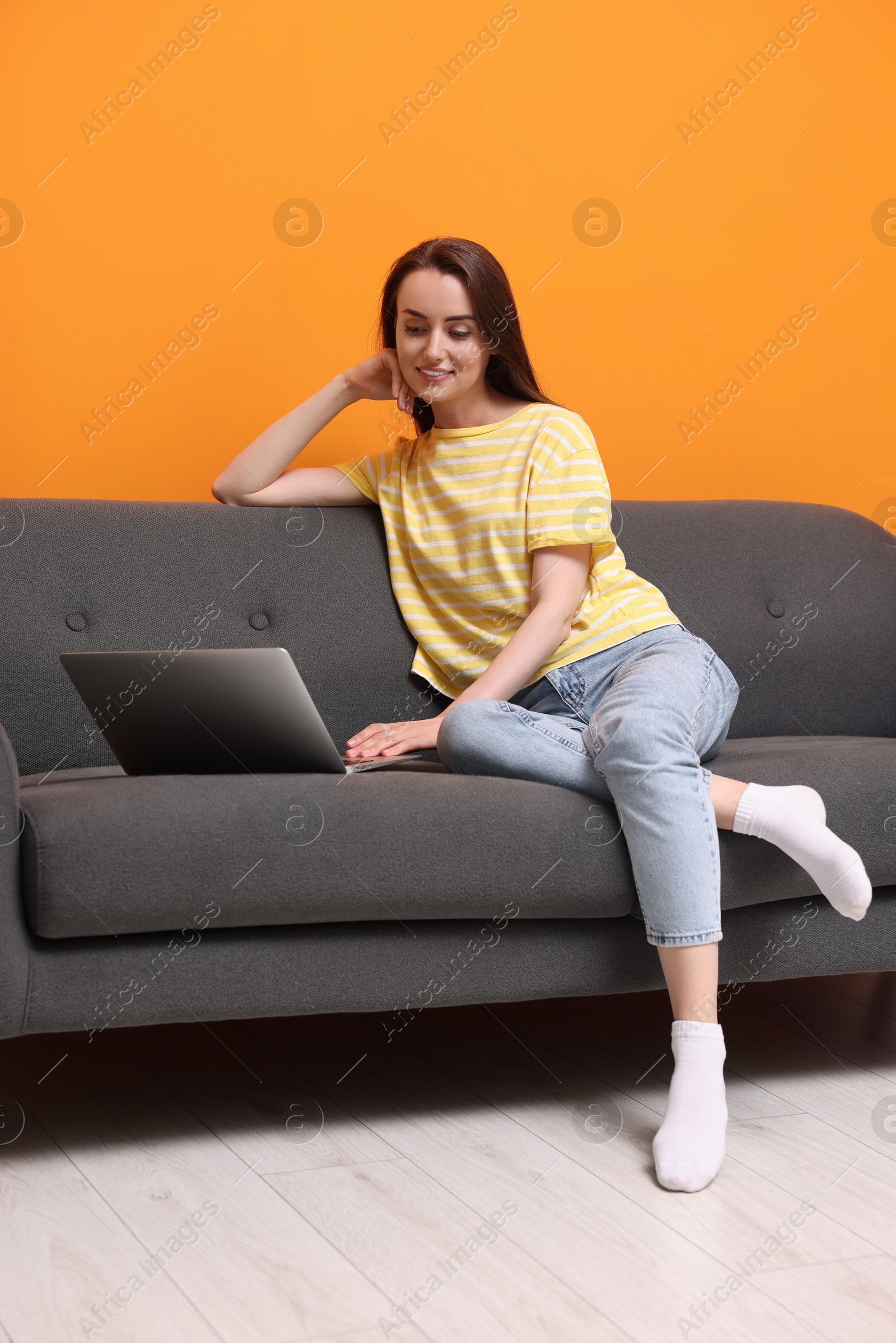 Photo of Smiling woman with laptop on sofa at home