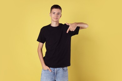 Photo of Teenage boy wearing black t-shirt on yellow background