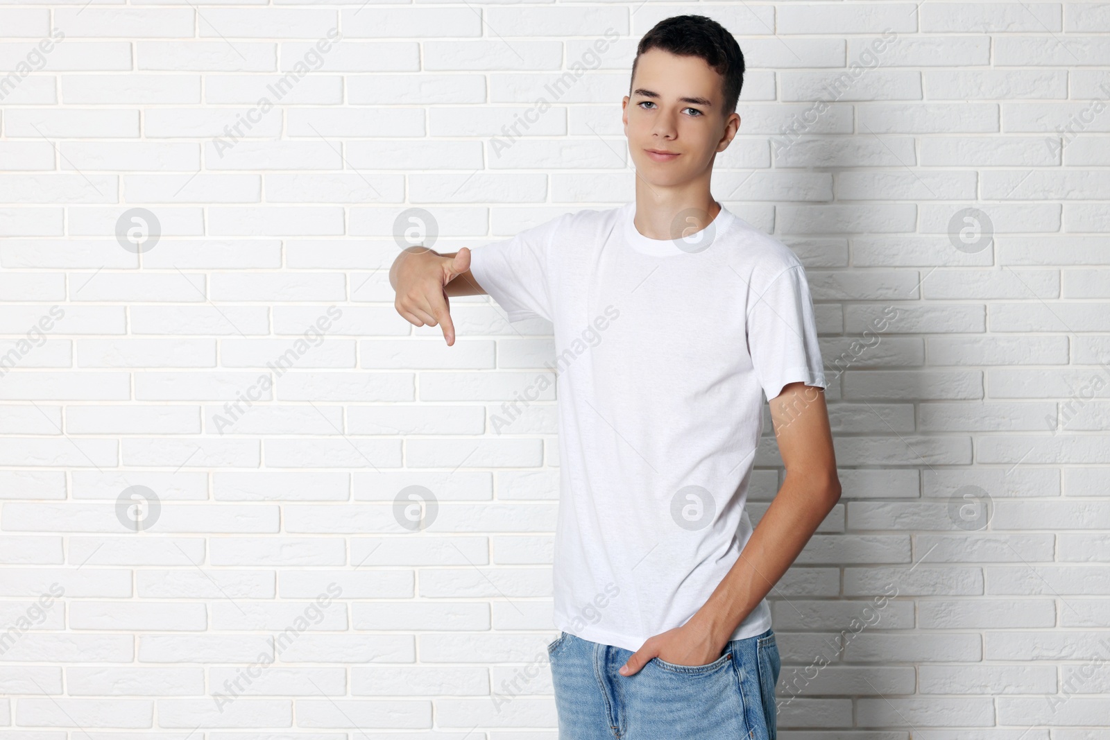 Photo of Teenage boy wearing t-shirt near white brick wall, space for text