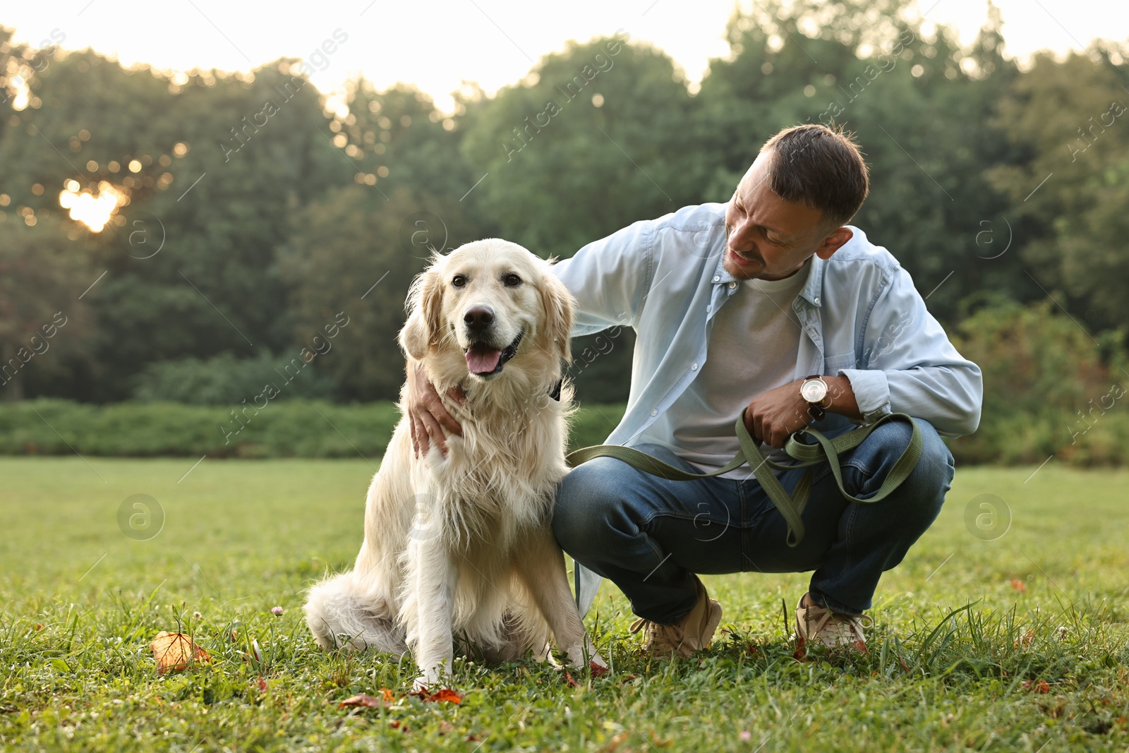 Photo of Smiling man with cute Golden Retriever dog on spring day