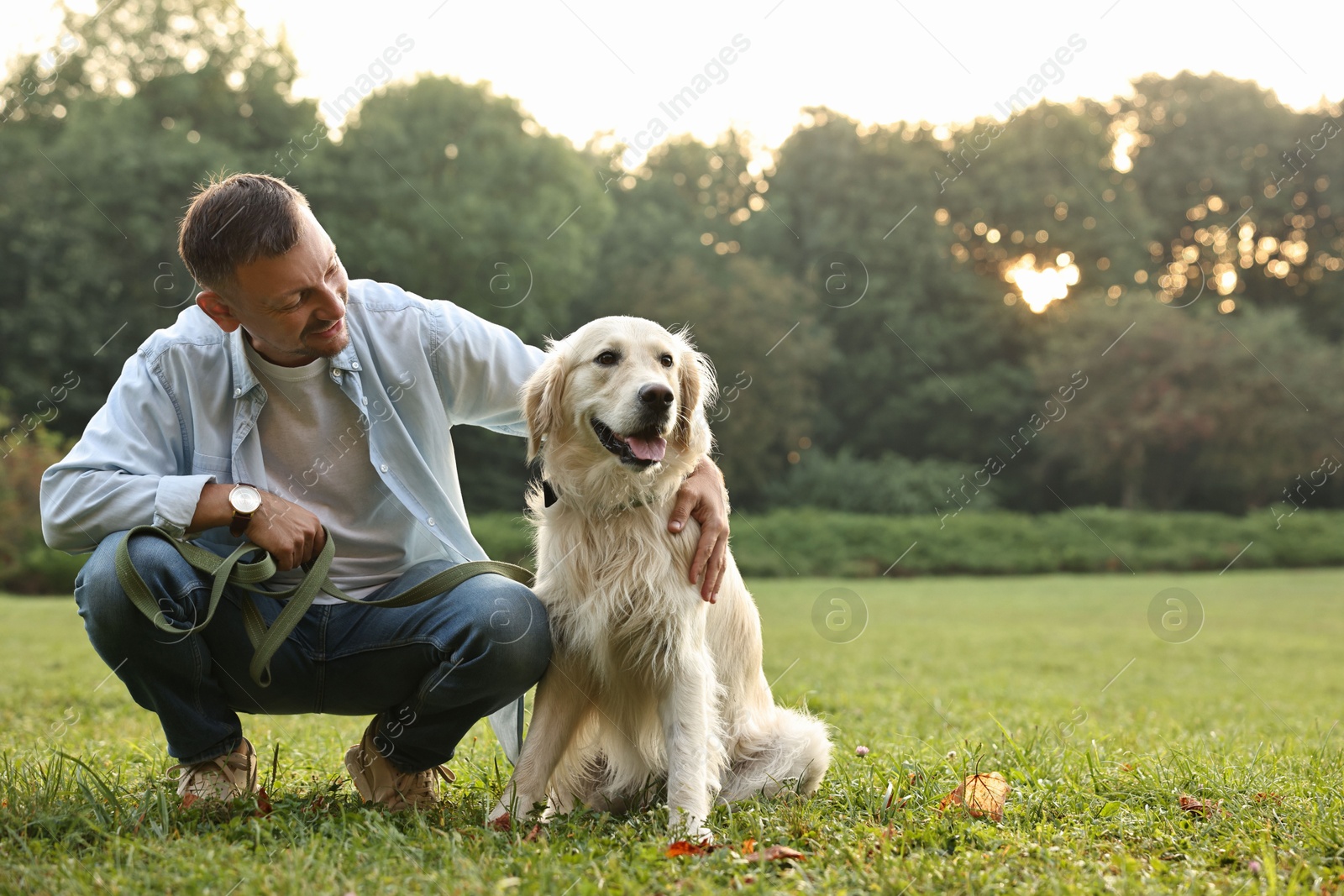 Photo of Smiling man with cute Golden Retriever dog on spring day, space for text