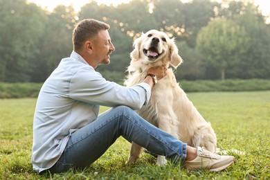 Smiling man with cute Golden Retriever dog on spring day