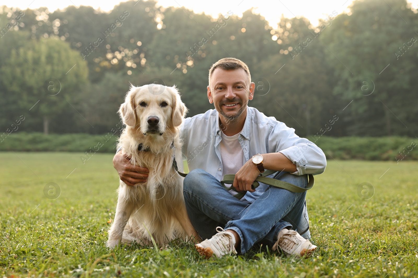 Photo of Smiling man with cute Golden Retriever dog on spring day