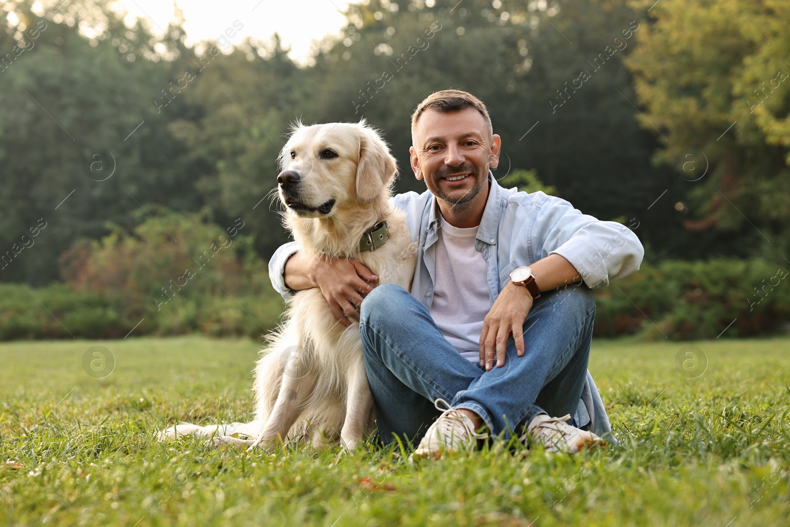 Photo of Smiling man with cute Golden Retriever dog on spring day