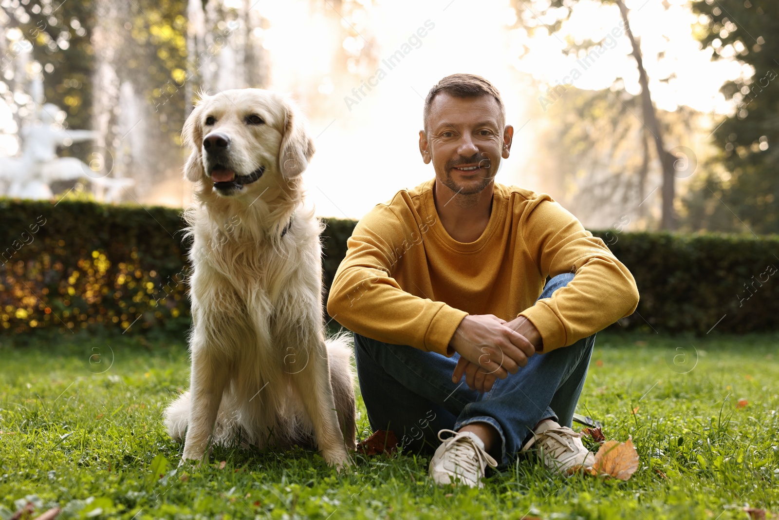 Photo of Smiling man with cute Golden Retriever dog on spring day