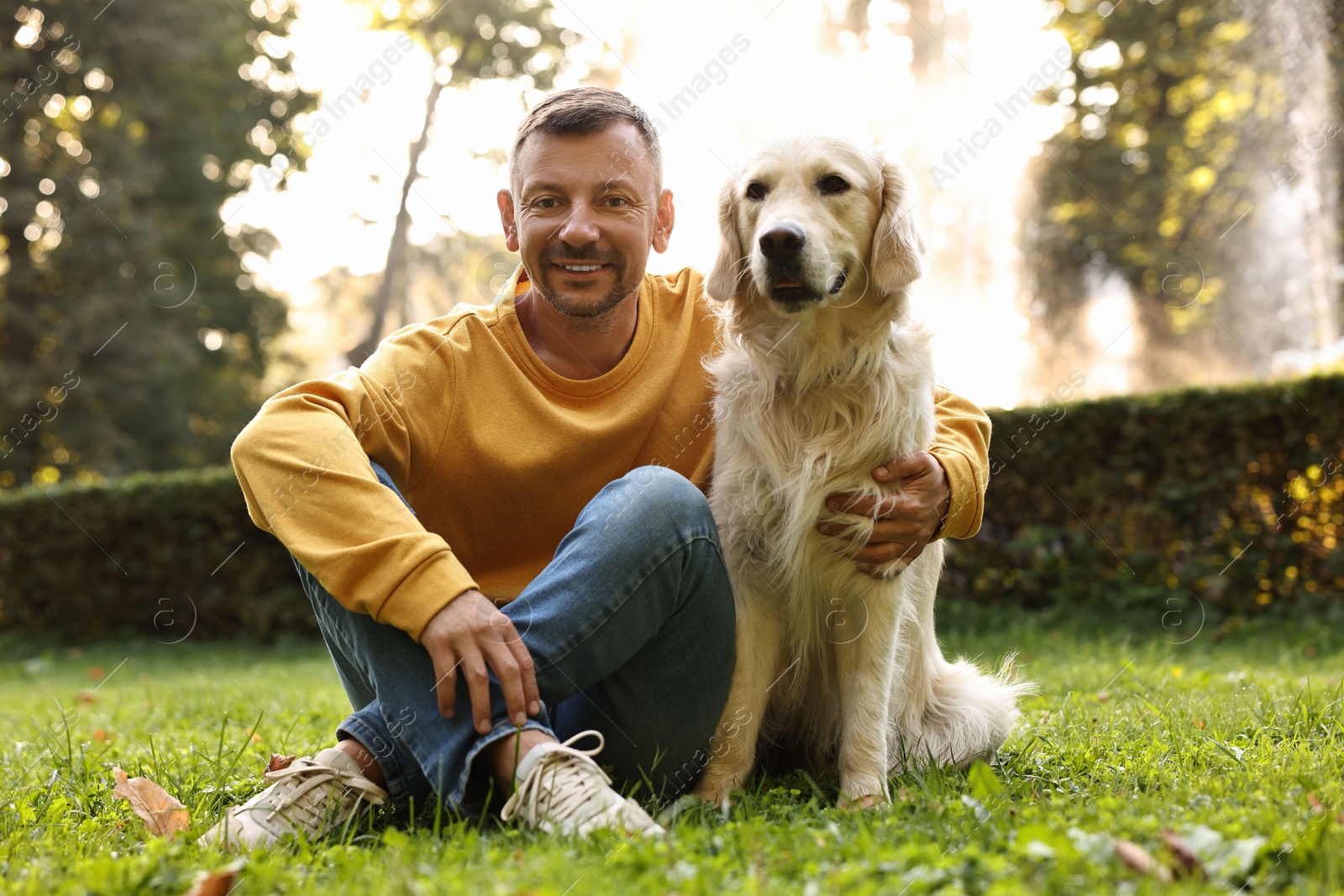 Photo of Smiling man with cute Golden Retriever dog on spring day