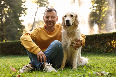 Smiling man with cute Golden Retriever dog on spring day