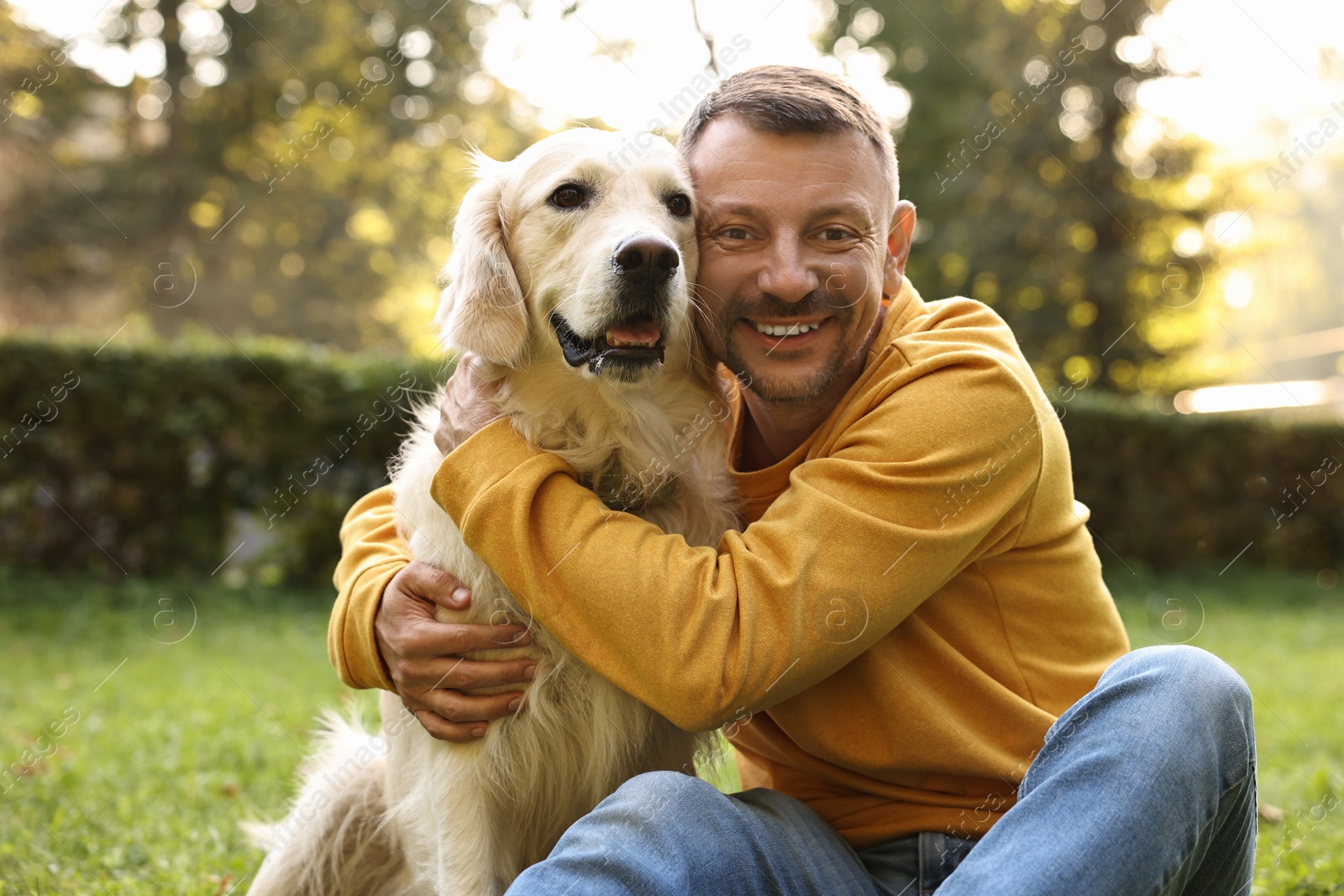 Photo of Smiling man with cute Golden Retriever dog on spring day