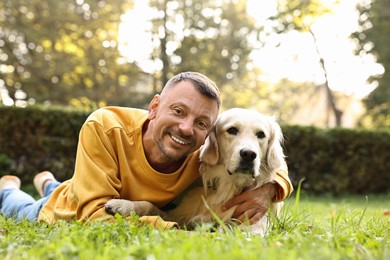 Photo of Smiling man with cute Golden Retriever dog on spring day