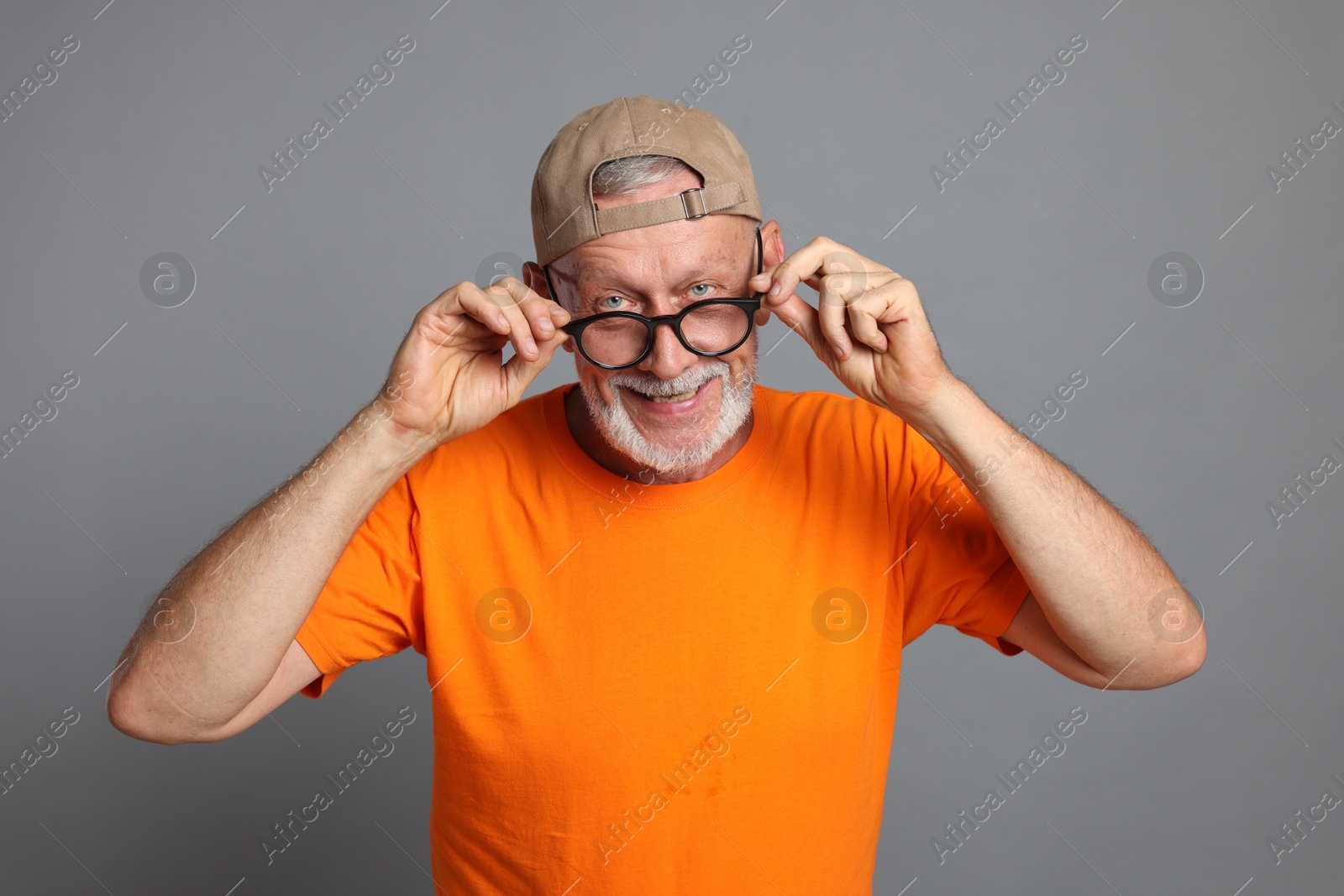 Photo of Portrait of funny senior man in glasses on grey background