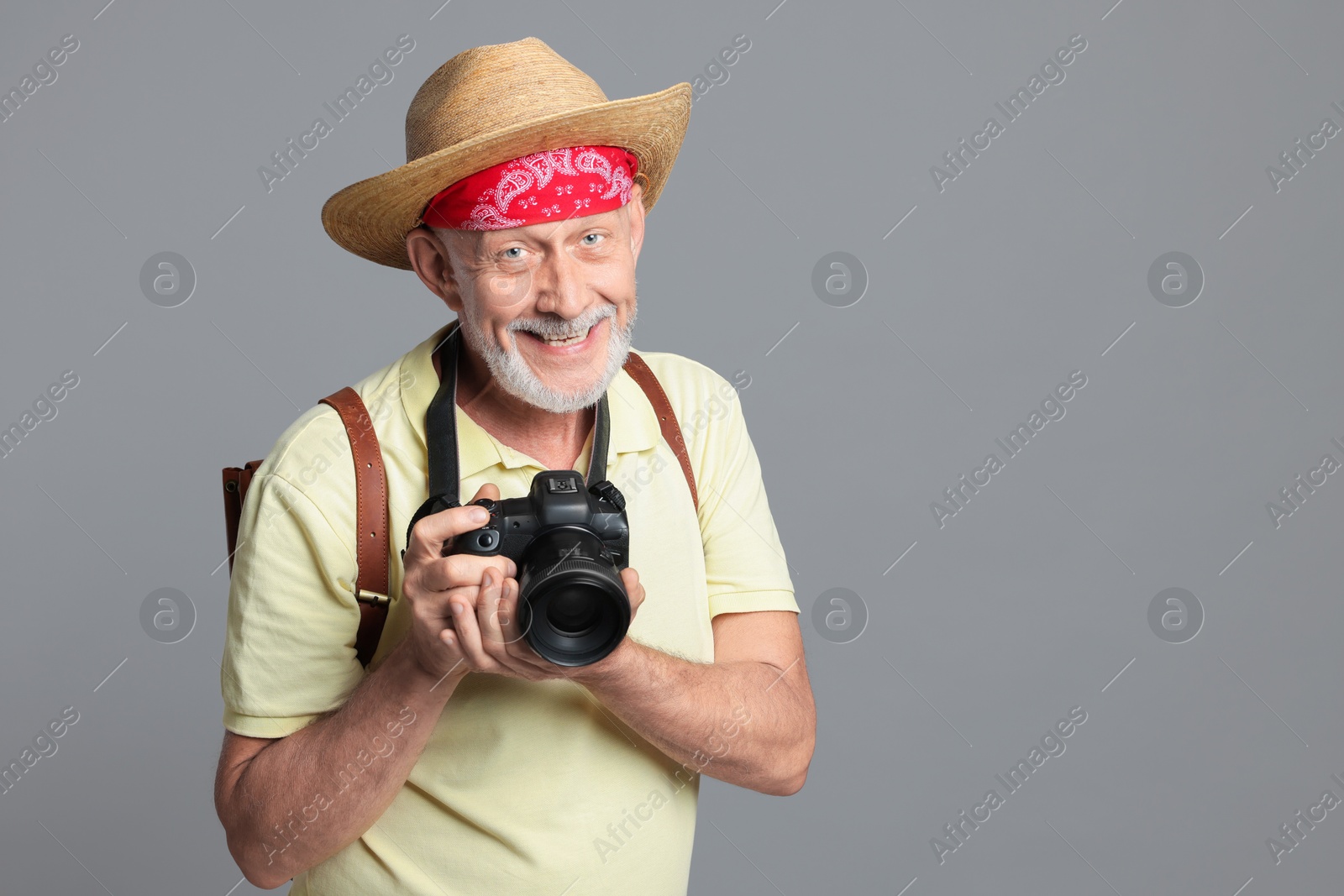 Photo of Portrait of happy senior man with camera on grey background. Space for text