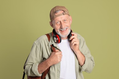 Portrait of happy senior man with headphones on green background