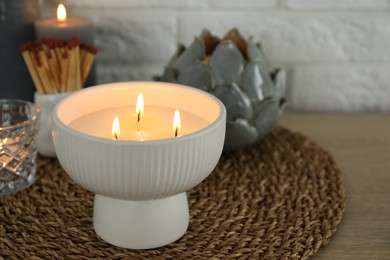 Burning candles and decor on table near white brick wall