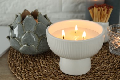 Photo of Burning candle and decor on table near white brick wall