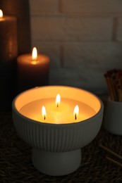 Photo of Burning candles and decor on table near white brick wall