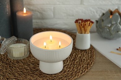 Burning candles and decor on table near white brick wall