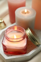 Beautiful burning candles on fabric against blurred lights, closeup