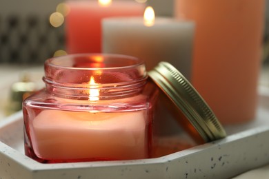 Beautiful burning candles on fabric against blurred lights, closeup