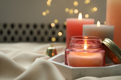 Beautiful burning candles on fabric against blurred lights. Space for text