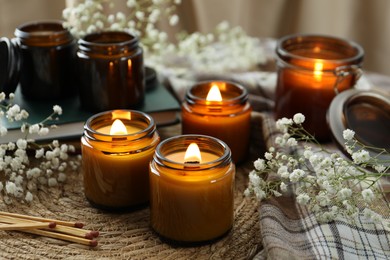 Photo of Burning candles and beautiful flowers on table