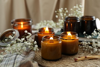 Burning candles and beautiful flowers on table