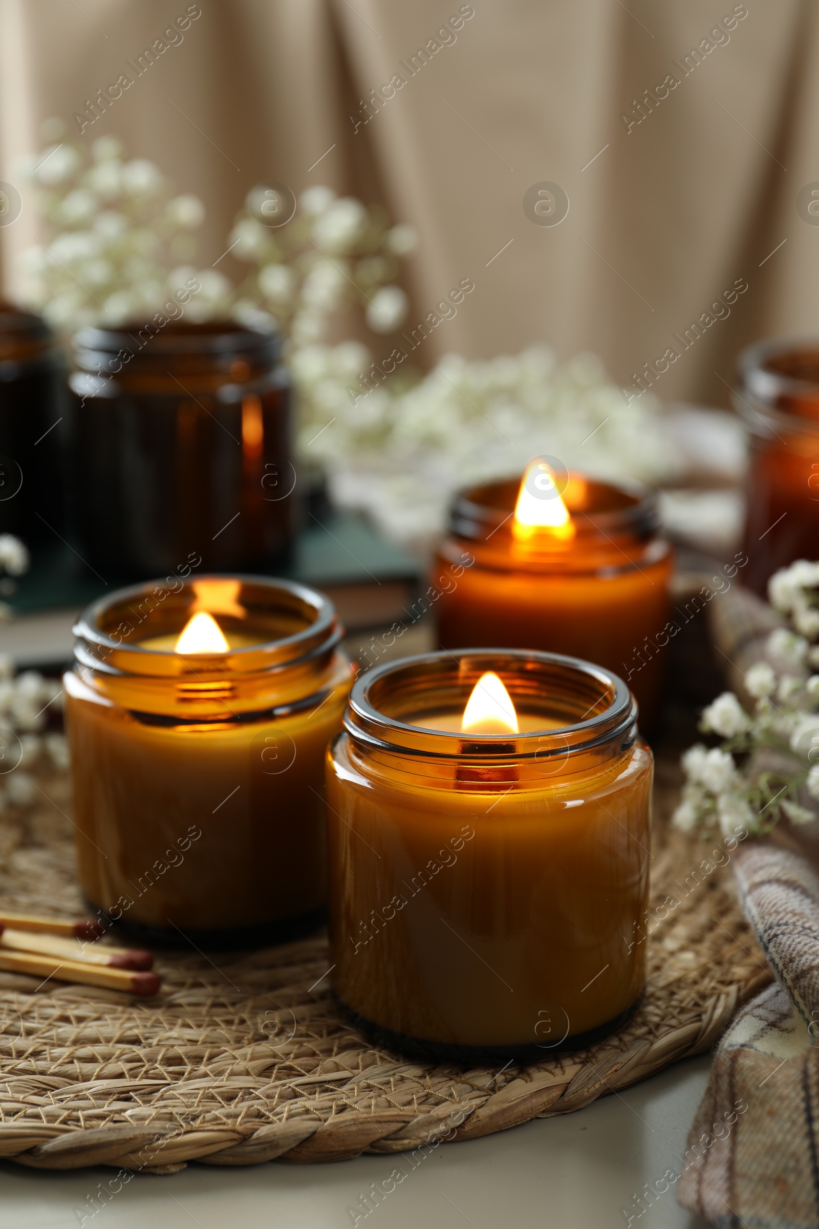 Photo of Burning candles and beautiful flowers on table