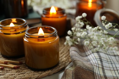 Burning candles and beautiful flowers on table