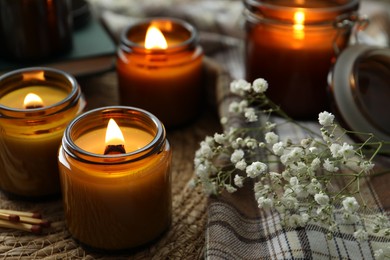 Photo of Burning candles and beautiful flowers on table