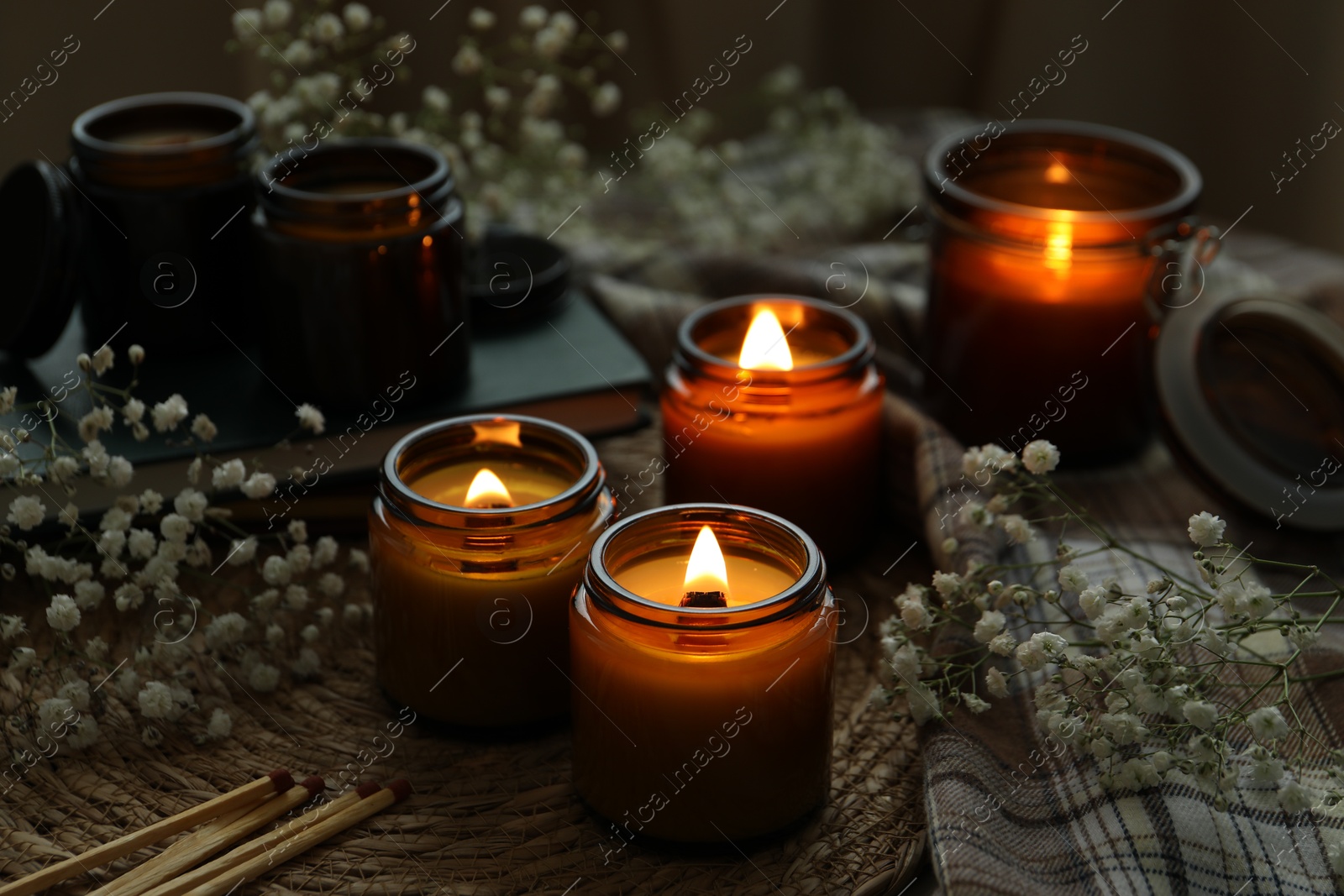 Photo of Burning candles and beautiful flowers on table