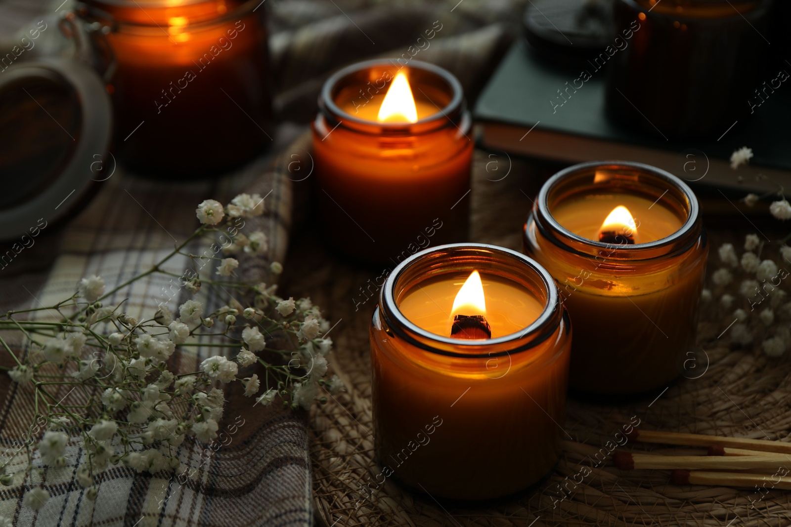 Photo of Burning candles and beautiful flowers on table