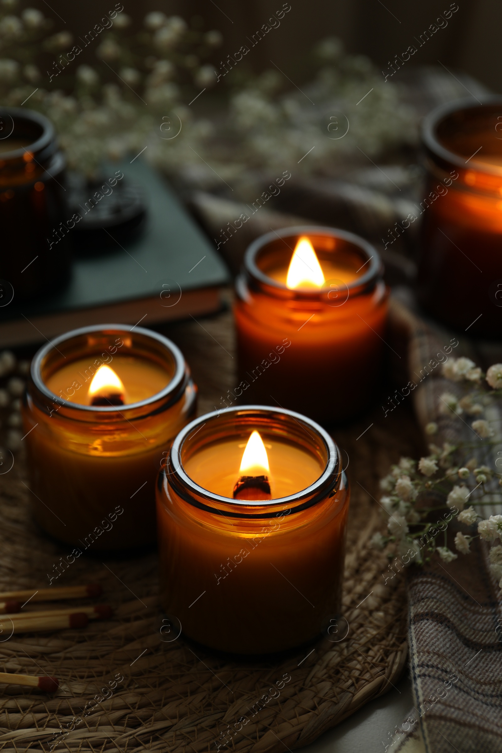 Photo of Burning candles and beautiful flowers on table