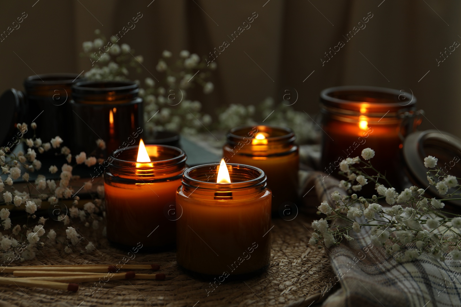 Photo of Burning candles and beautiful flowers on table