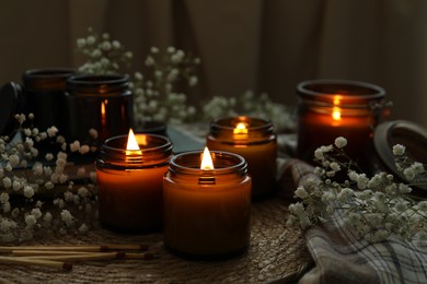 Photo of Burning candles and beautiful flowers on table